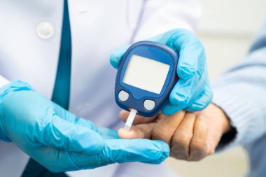Diyabet tedavisinde kan şekeri seviyesini kontrol etmek için dijital glikoz ölçer kullanan Asyalı doktor.