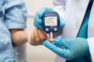 Diyabet tedavisinde kan şekeri seviyesini kontrol etmek için dijital glikoz ölçer kullanan Asyalı doktor.