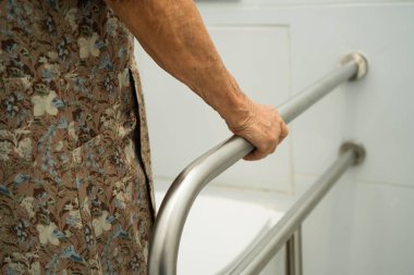 Asyalı yaşlı kadın hasta tuvalette tuvalet desteği kullanıyor..