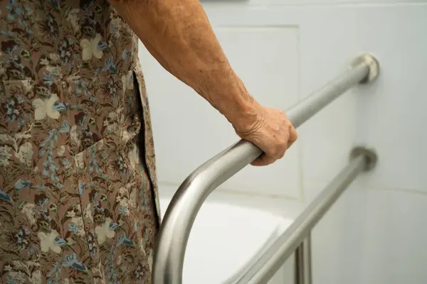 Asyalı yaşlı kadın hasta tuvalette tuvalet desteği kullanıyor..