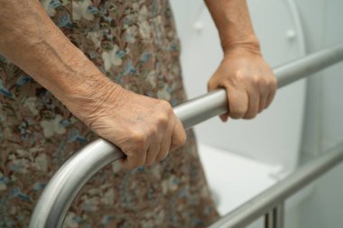 Asyalı yaşlı kadın hasta tuvalette tuvalet desteği kullanıyor..