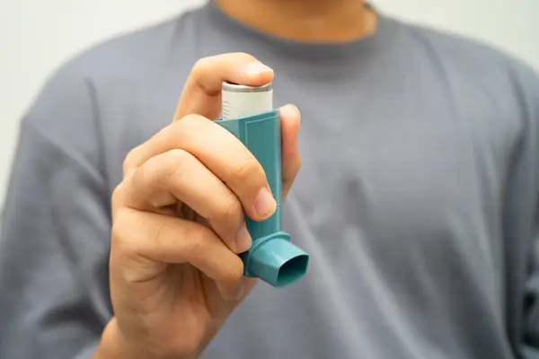Astım ve kronik obstrüktif akciğer hastalığı COPD, Asyalı genç adam ölçülü doz solunum cihazı kullanıyor..