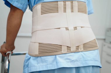 Bel ağrısı çeken Asyalı bir kadın. Hastanede yürüteç kullanıyor..