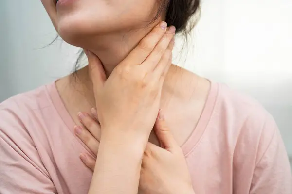 Tiroit bezi sorunu için boynuna ve boğazına dokunan Asyalı kadın..