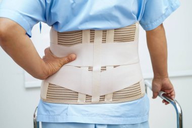 Bel ağrısı çeken Asyalı bir kadın. Hastanede yürüteç kullanıyor..