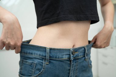 Genç Asyalı kadın, bol bol pantolon giyerek kilo veriyor..