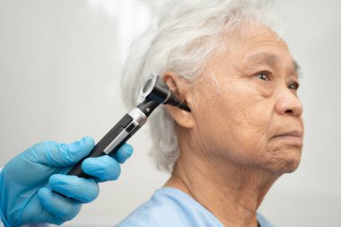 Otolaryngologist ya da ENT hekim doktoru yaşlı hasta kulağını otoskopla muayene ediyor, işitme sorunu var..