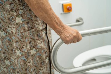 Asyalı yaşlı kadın hasta tuvalette tuvalet desteği kullanıyor..