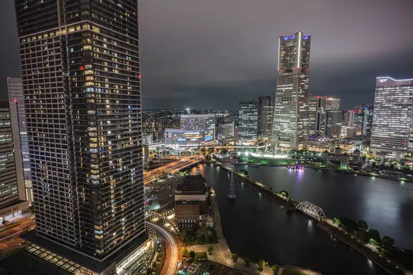 Bu görüntü, bir otelden alınan Yokohama Minato Mirai 'nin gece görüşünü gösteriyor. Şehir manzarasında aydınlık gökdelenler, yollar ve deniz manzarası yer almaktadır..