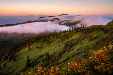 This attached photo shows the view from a mountain peak reached by car early in the morning, with the mountains illuminated by the morning sun (alpenglow). clipart