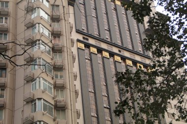 Yüksek katlı bir binanın ön cephesi resmedilmiş..