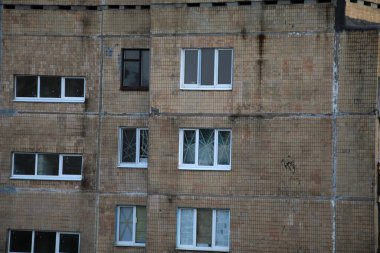Pencereleri cam şeritleri ile çapraz yapıştırılmış çok katlı bir binanın kasvetli cephesi.