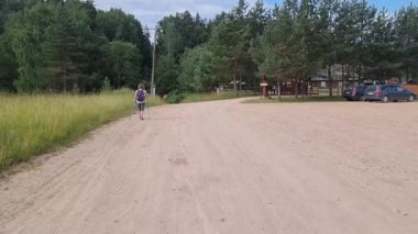 Sırt çantalı bir kadın kumlu bir köy yolunda yürüyor. Yüksek kalite 4k görüntü