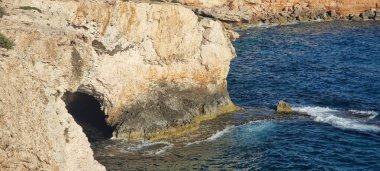 Kireçtaşı kayalıklara oyulmuş dramatik bir deniz mağarası Kıbrıs Rum Kesimi 'nin Cape Greco kenti yakınlarındaki Akdeniz' in turkuaz sularıyla kesişiyor. Engebeli arazi ve berrak mavi deniz, el değmemiş adaları kaplıyor.