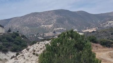 Kıbrıs Rum Kesimi 'nin kırsal kesimindeki kayan tepeler ve engebeli dağların panoramik manzarası, dağınık bitki örtüsü ve kırsal kesimlerin yol aldığı bir manzara. Sakin doğal manzara projeler için idealdir.