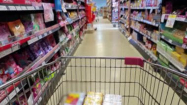 Süpermarketin koridorundaki raflarda bir ürünle alışveriş arabasında. Ürün satın alınıyor