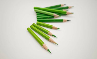 Beyaz arkaplanda yeşil renkli kalemler.