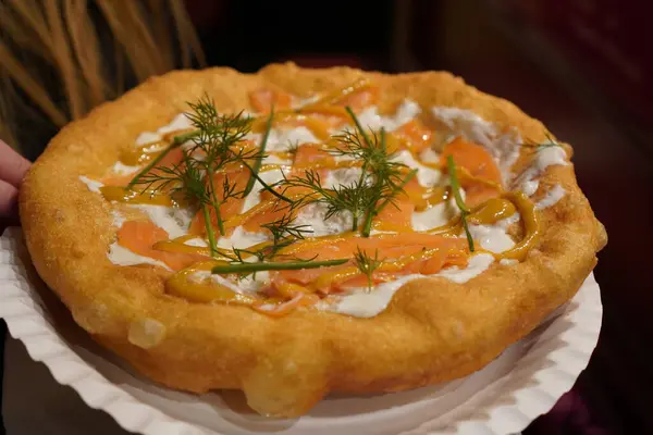 Bir langoya yakın, tipik Macar yemek spesiyali, ekşi krema ve balık somonuyla kahverengi bir tabakta, bol yağda kızartılmış hamur.