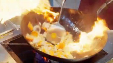 Şef aşçı mutfakta. Restoranda tavada yemek pişirmek. Çin yemeklerini kavurucu ateşle pişirmeye yakın çekim. Yavaş çekim 4K video