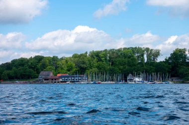 Kıyısında küçük bir kasaba olan bir su kütlesi. Su sakin ve gökyüzü mavi.