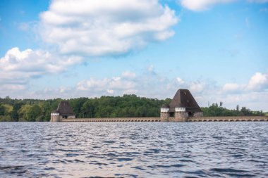 A serene body of water with two charming wooden buildings situated on either side of a bridge. The buildings are small and quaint, giving the scene a peaceful and picturesque atmosphere clipart