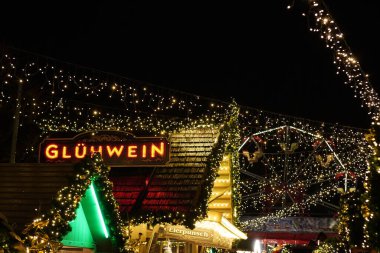 Üzerinde Gluhwein yazan bir Noel mağazası. Mağaza ışıklarla süslenmiş ve yeşil bir çatısı var.