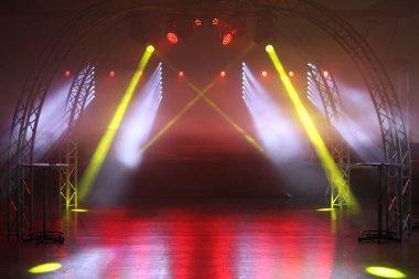 Kırmızı ve sarı ışık gösteren büyük, açık bir alan. Işıklar, derinlik ve hareket hissi yaratacak şekilde sıralanmış. Alan boş, görünür insan ya da nesne yok.