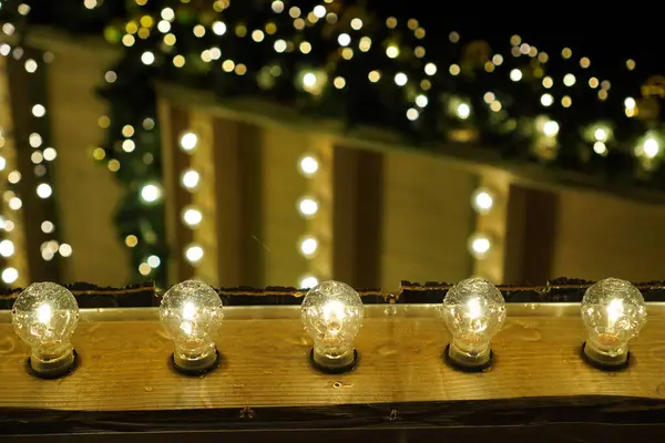 Bir sıra Noel ışığı yanıyor ve ahşap bir kirişe asılıyor. Işıklar sıraya dizilir ve aydınlatılır. Sıcak ve şenlikli bir atmosfer yaratır.