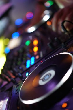 Bir DJ ekipmanlarını hazırlıyor. Pikabını ve mikserini de. Pikabın dönmesi ve mikser açık. DJ 'in müziği karıştırıp yaratması için hazır.