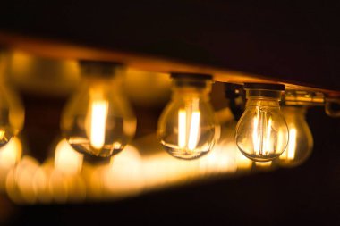 Bir sürü ampul yanıyor ve tavandan sarkıyor. Ampullerin hepsi farklı boyutlarda ve renklerde. Sıcak ve davetkar bir atmosfer yaratıyorlar.