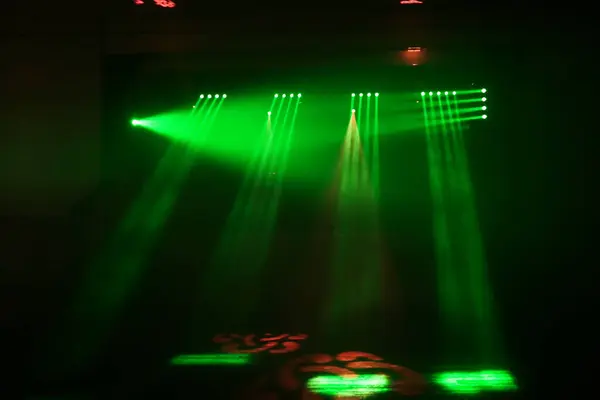 Koyu bir geçmişi olan yeşil ışık gösterisi. Işıklar açık ve oda karanlık.