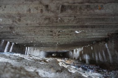 Beton zemini olan büyük, boş bir yer. Mekan enkaz ve toprakla dolu, kirli ve terk edilmiş bir görünüm veriyor. Boşluğun boşluğu.