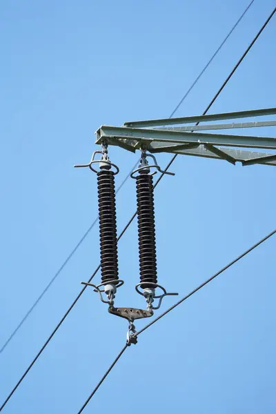 İki elektrik hattı bir direğe bağlı. Direk havada ve gökyüzü mavi.