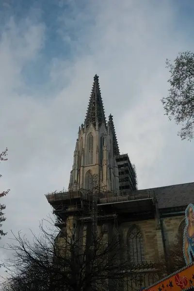 Çan kulesi ve üzerinde haç olan uzun, eski bir kilise. Gökyüzü bulutlu ve güneş görünmüyor.