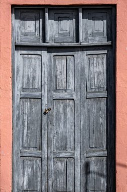 Kilitli ve anahtar delikli bir kapı. Kapı ahşaptan yapılmış ve kırsal bir görünüme sahip.