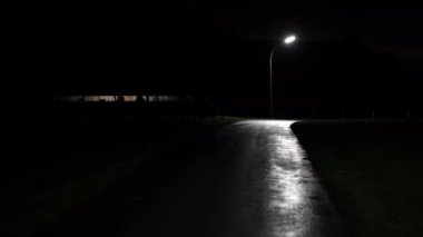 Üzerinde sokak lambası parlayan ıssız bir yol. Yolun kenarında bir tabela var, ama ne yazdığı belli değil. Sokaklar bomboş ve etrafta ne araba ne de insan var.