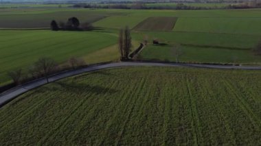 İçinden yol geçen büyük bir tarla. Yol boş ve gökyüzü temiz.