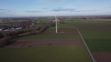 Uzakta bir rüzgar türbini görülür, bir çimen tarlası ile çevrilidir. Rüzgâr türbini, rüzgârın gücünü elektrik üretmek için kullanırken, doğayla uyum ve huzur kavramı.
