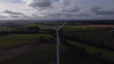 Arka planda bulutlu bir gökyüzü olan bir rüzgar türbini uzaktan görülür. Rüzgâr türbini açık alanda gururlu ve dimdik dururken sakin ve huzurlu olma kavramı.