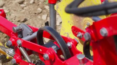 Sarı gidonu olan kırmızı bir traktör. Traktör tarlada.