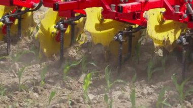 Toprakta sarı ve kırmızı renkli bir traktör var. Traktör çiftçilik için kullanılıyor.