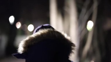 Bir kişi siyah bir ceket ve şapka giyiyor. Görüntü koyu ve bulanık, kişinin kafasına odaklanmış.