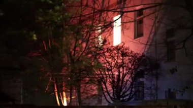 Arka planda bina olan karanlık bir gece. Bina kırmızı bir parıltıyla aydınlanıyor.