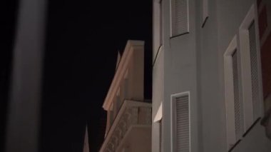 Yan tarafında pencere olan bir bina var. Pencere açık. Bina yüksek ve bir sürü penceresi var.