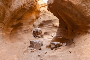 Ortasında büyük bir kaya olan dar bir kanyon. Kanyon kayalar ve toprakla dolu.