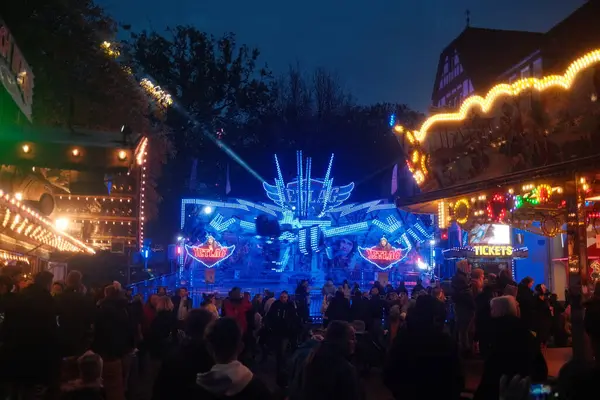 Merkezinde büyük mavi bir araba olan bir karnaval. İnsanlar etrafta dolanıp eğleniyorlar.