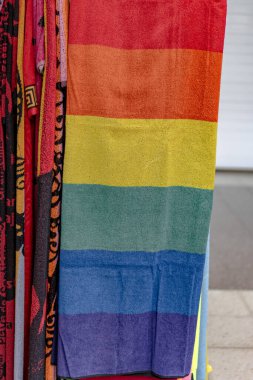Duvarda gökkuşağı çizgili renkli bir eşarp asılı. Eşarp yumuşak, pelüş bir malzemeden yapılmış ve eşsiz bir tasarımı var. Eşarbın renkleri canlı ve göz alıcı.