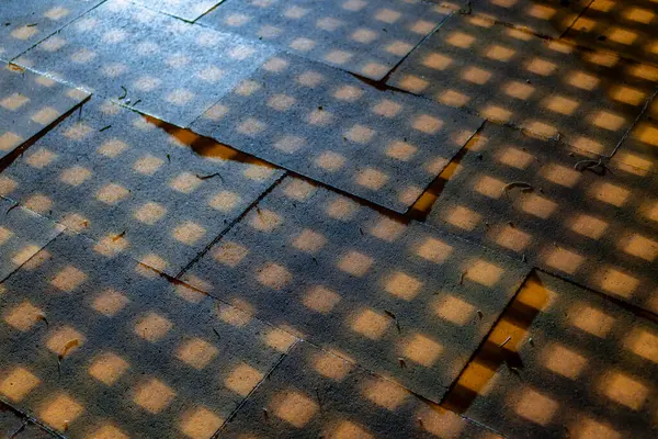 Bir insanın gölgesi olan kareli bir zemin. Zemin tahtadan ve gölge de karanlıktan yapılmıştır.