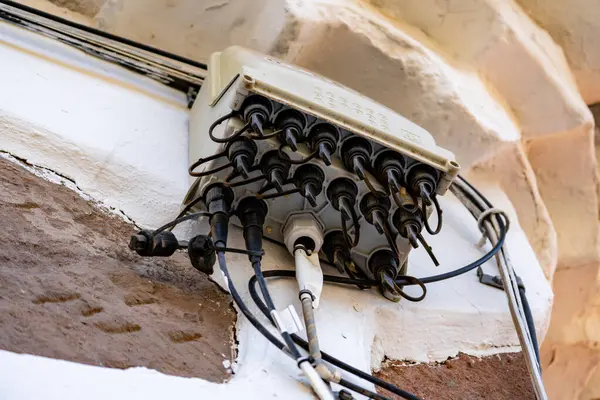 Duvardan sarkan bir sürü kablo. Kablolar birbirine dolanmış ve eski gibi görünüyor. Görüntü biraz kaotik ve düzensiz.