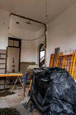 Yerde siyah plastik bir çarşaf olan bir oda. Oda yenilenme sürecinde.